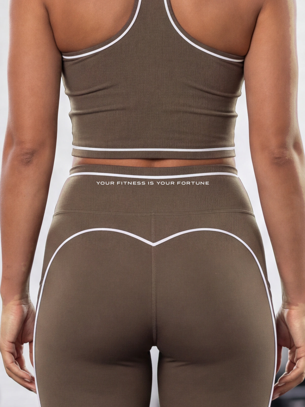 Close-up of the YFYF Outline leggings in Coffee from behind: white piping on the waistband edge with YOUR FITNESS IS YOUR FORTUNE printed beneath it