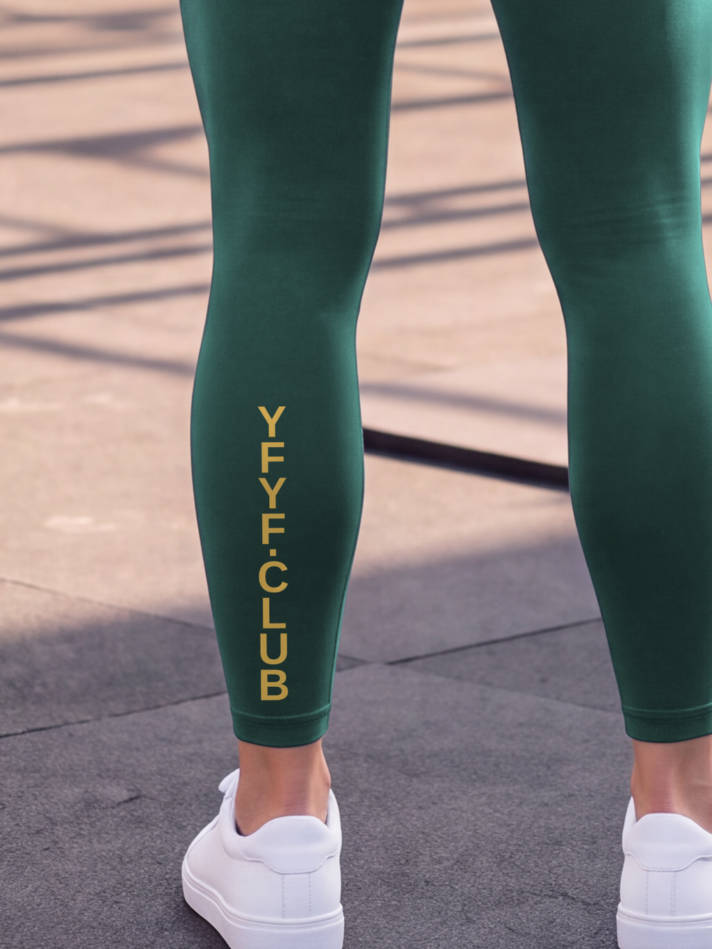 Close-up of the gold YFYF.CLUB print on the calf of the Dark Green Full Brand leggings