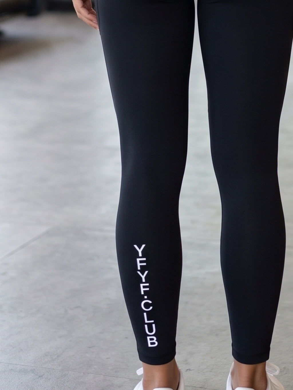Close-up of YFYF.CLUB printed on the calf of the Black White Logo leggings