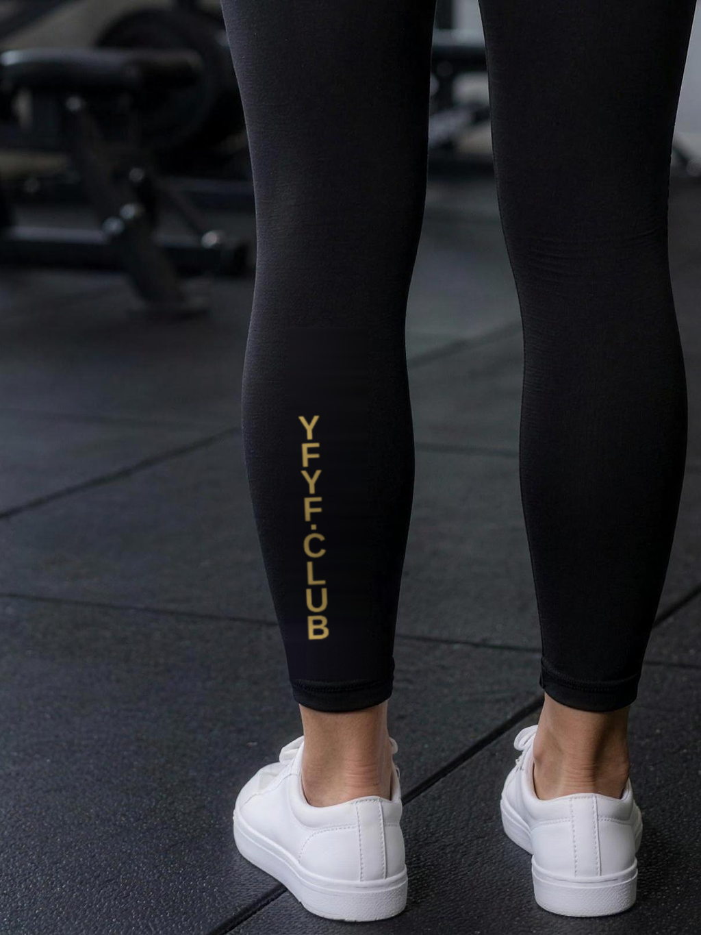 Close-up of gold YFYF.CLUB printed on the calf of the Black Gold Logo leggings