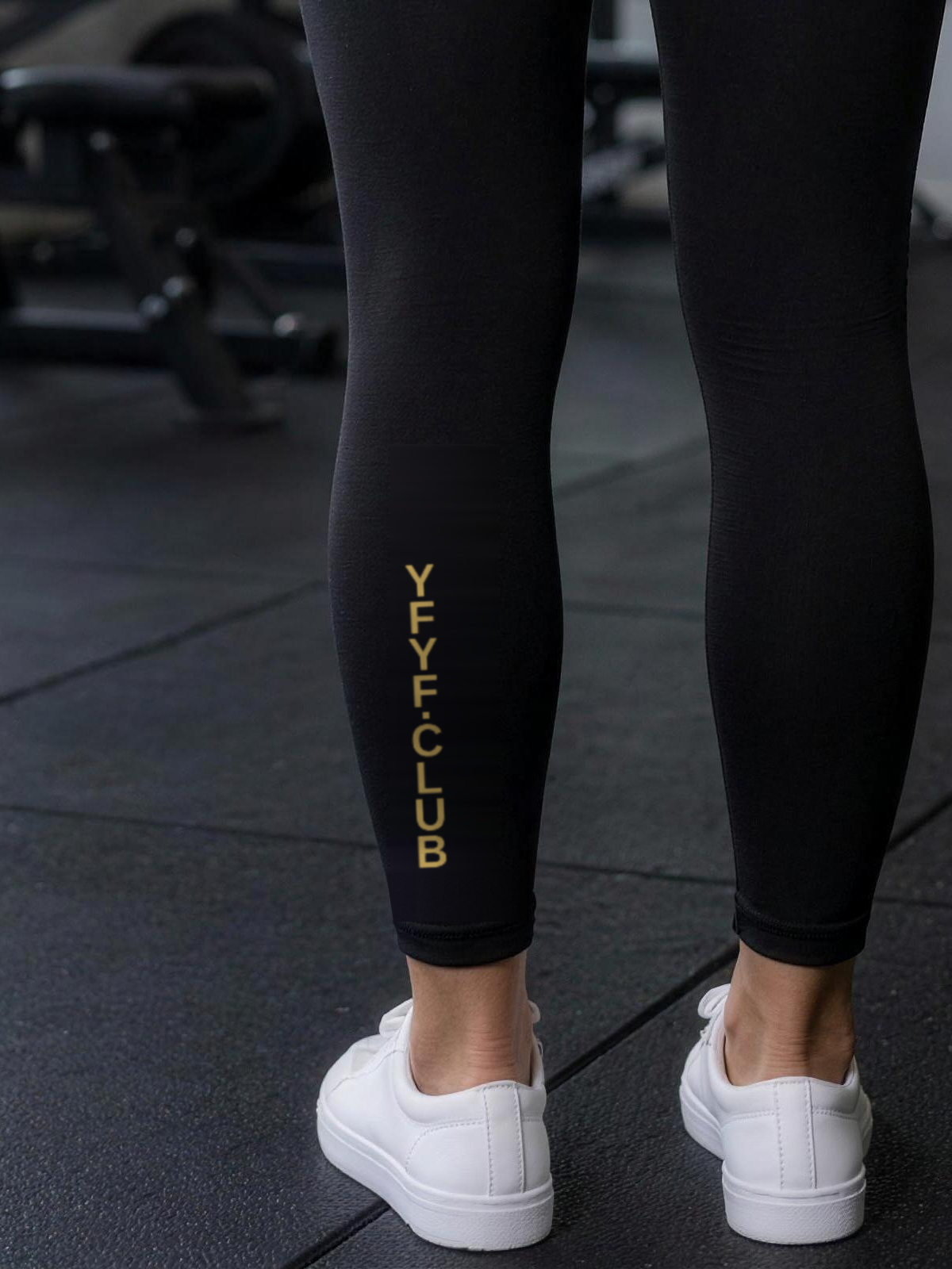 Close-up of gold YFYF.CLUB printed on the calf of the Black Gold Logo leggings