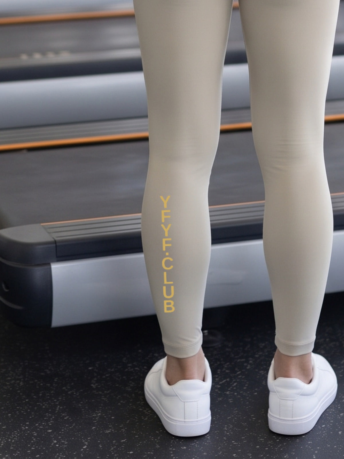 Close-up of gold YFYF.CLUB printed on the calf of the Light Gray Gold Logo leggings
