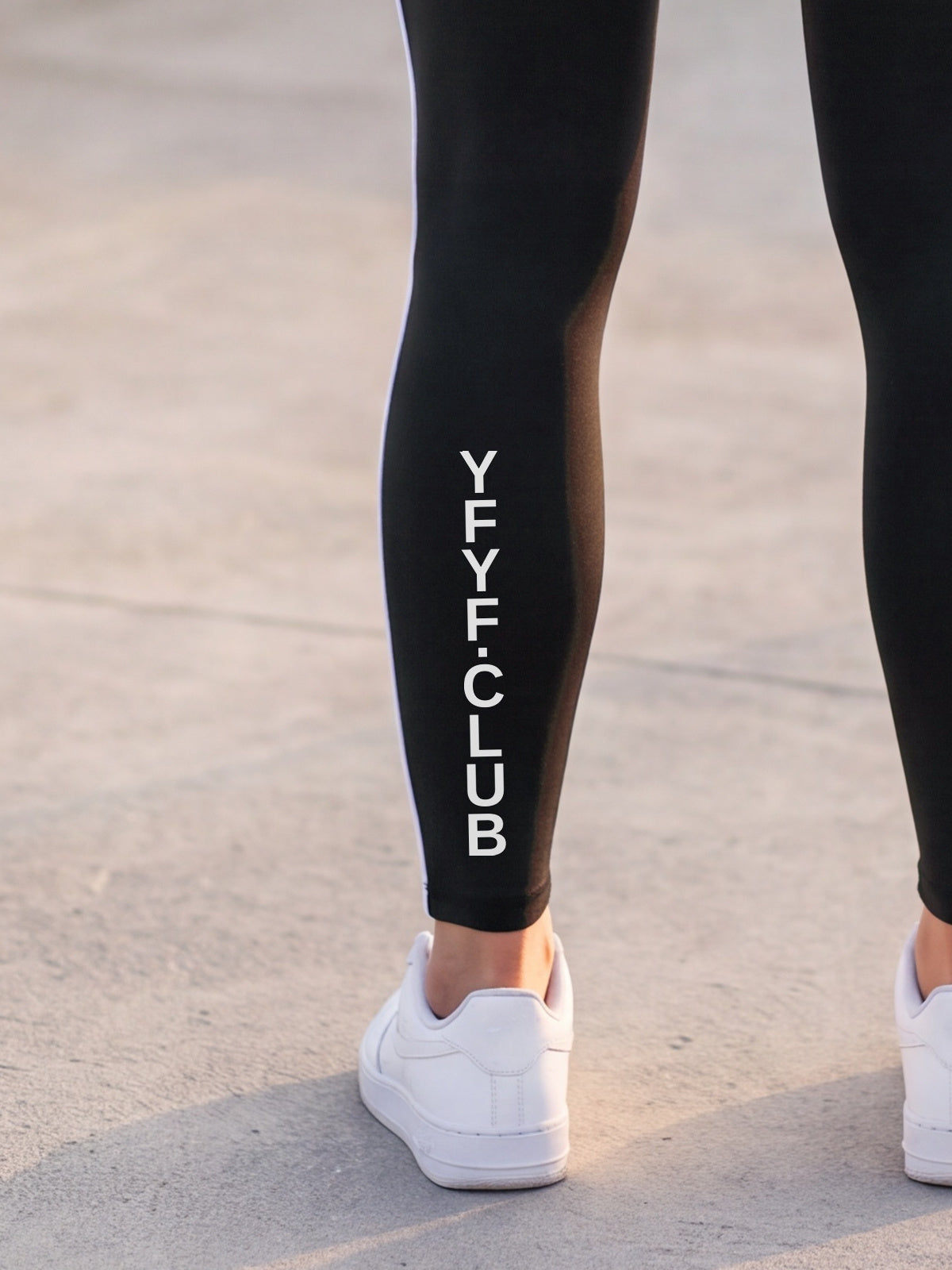 Close-up of the YFYF Outline leggings in Black: YFYF.CLUB printed on the left calf