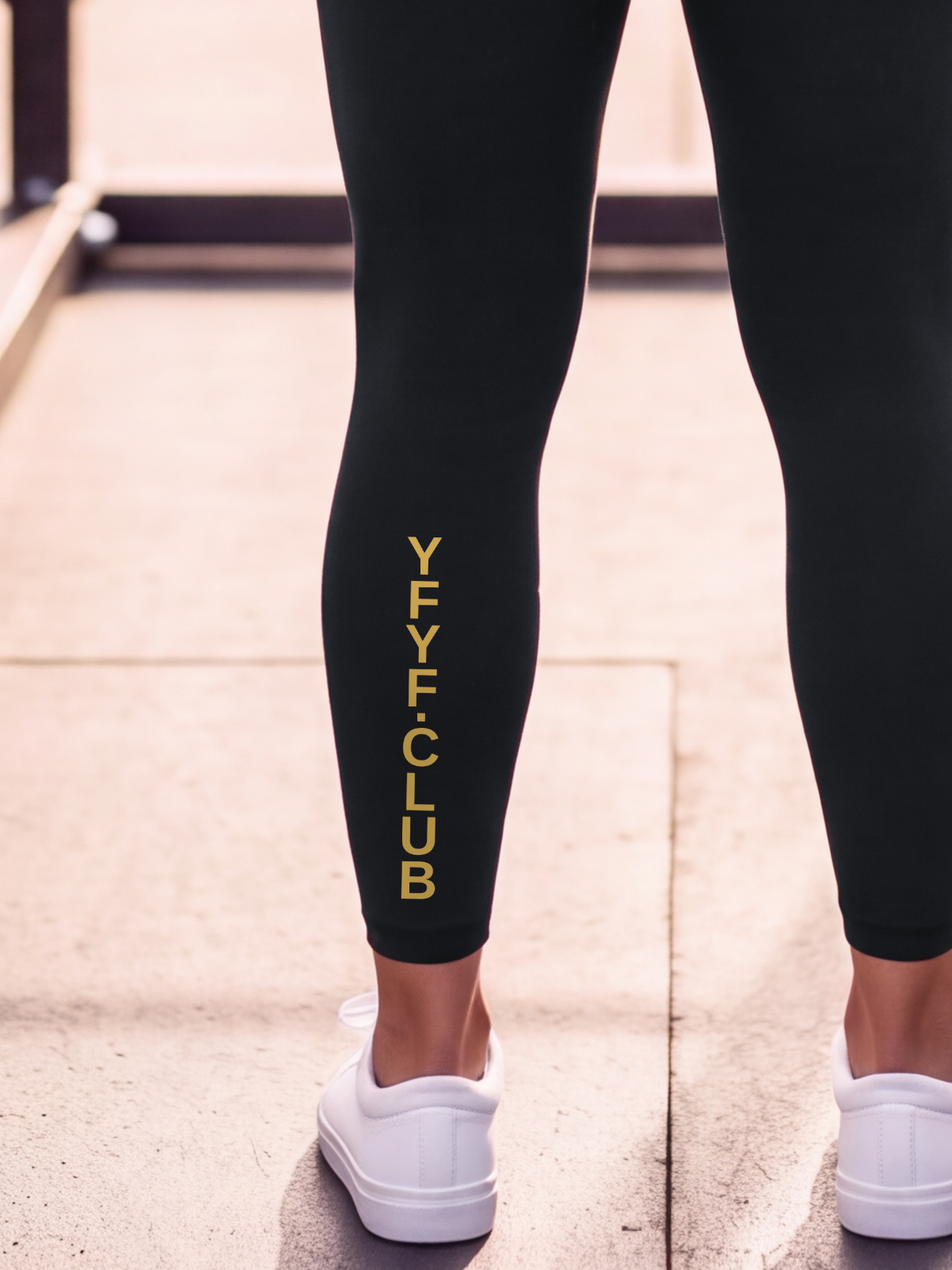 Close-up of the gold YFYF.CLUB print on the calf of the Black Full Brand leggings